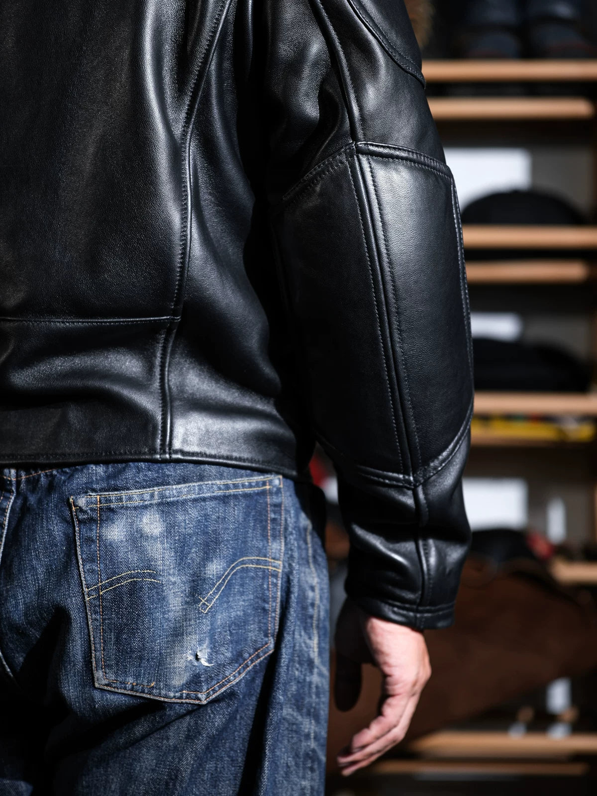 Back view of BRIXTON racing jacket in black sheepskin with panel seams