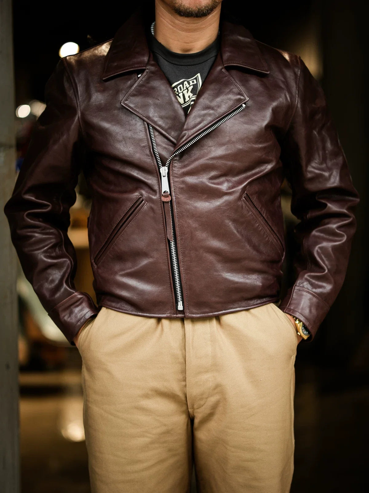 Model wearing seal brown water-dyed horsehide double-breasted aviator jacket open over tee and khaki trousers
