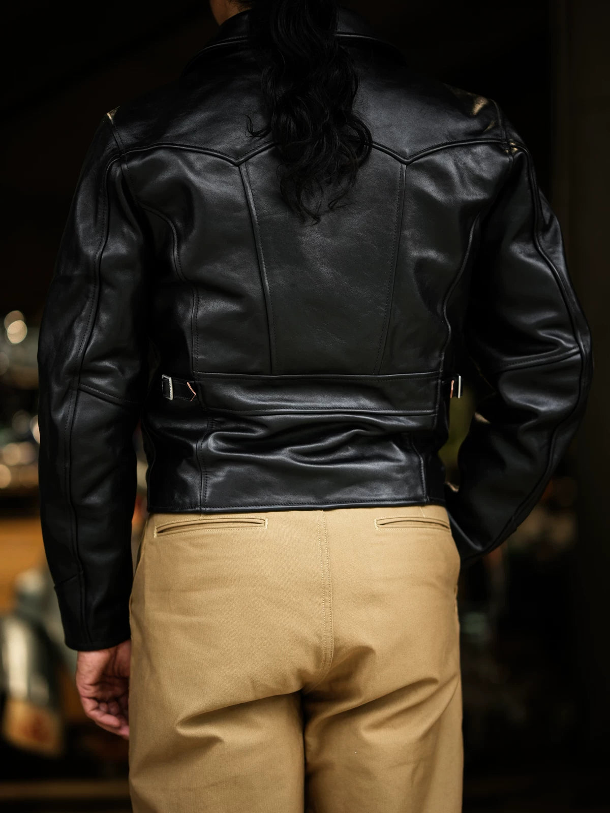 Back view showing parachute yoke, half-belt and side adjuster straps on black horsehide