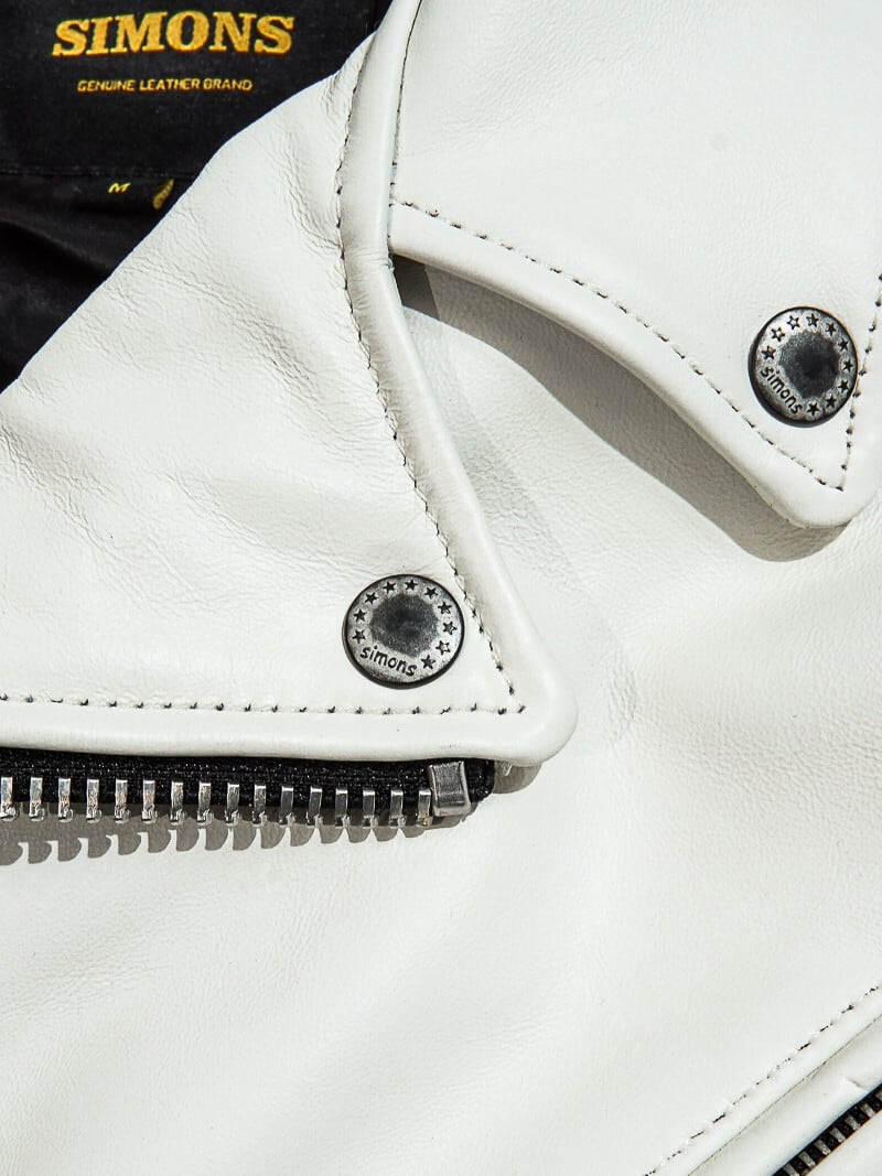 White jacket lapel detail with two-star SIMONS snap buttons and lining