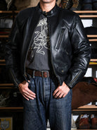 Real Simons BRIXTON café racer jacket in black sheepskin worn with denim, front view showing chest zip and waist flap pockets