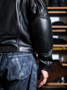 Back view of BRIXTON racing jacket in black sheepskin with panel seams