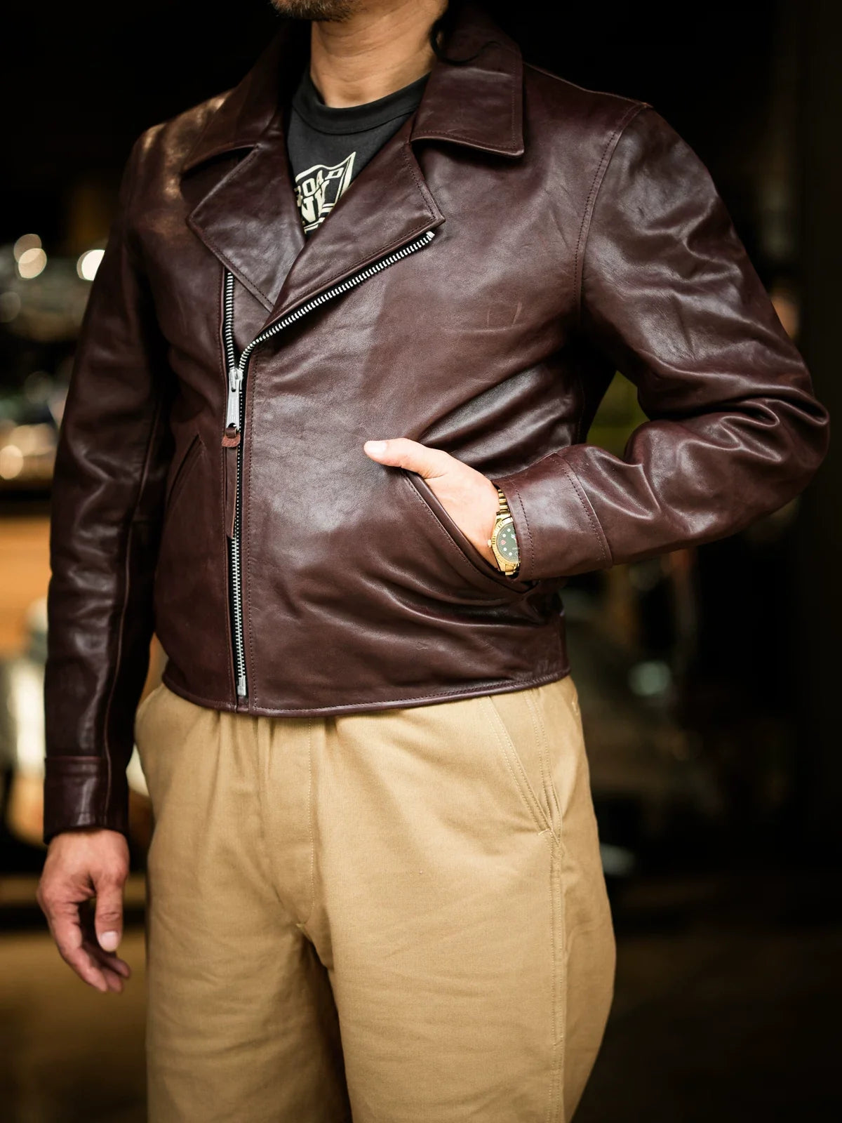 Three-quarter side view of seal brown horsehide jacket worn open, hand in muff pocket