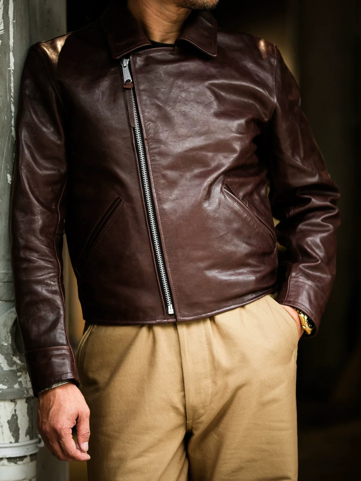 Seal brown horsehide aviator jacket zipped to stand collar, model leaning against concrete pillar