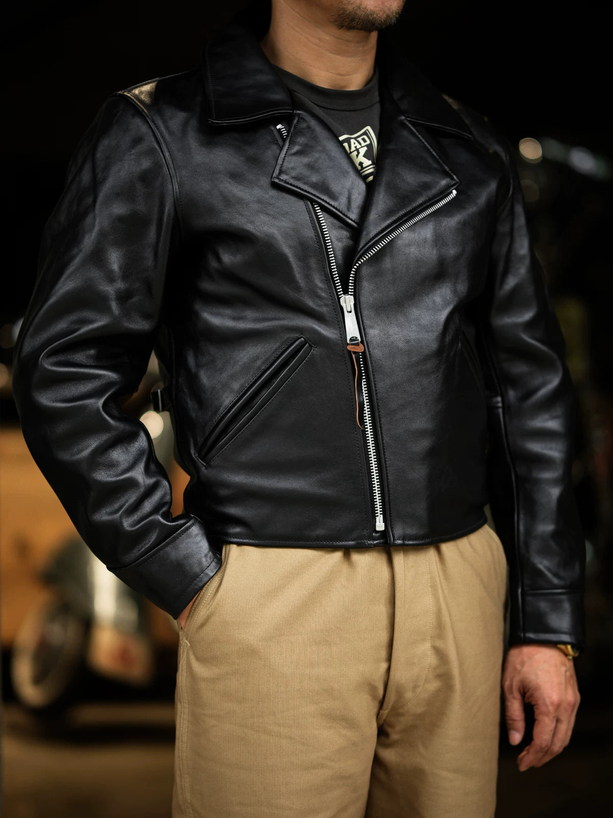 Three-quarter side view of black tea-core horsehide double-breasted jacket worn open