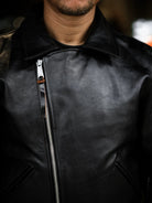 Close-up of diagonal antique metal zipper and wide lapel on black tea-core horsehide