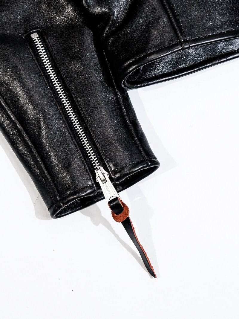 Black jacket cuff zipper detail with leather pull