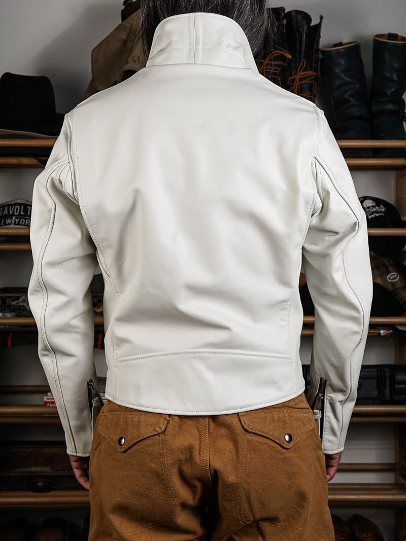 Back view of white beltless riders jacket with seaming and zip cuffs